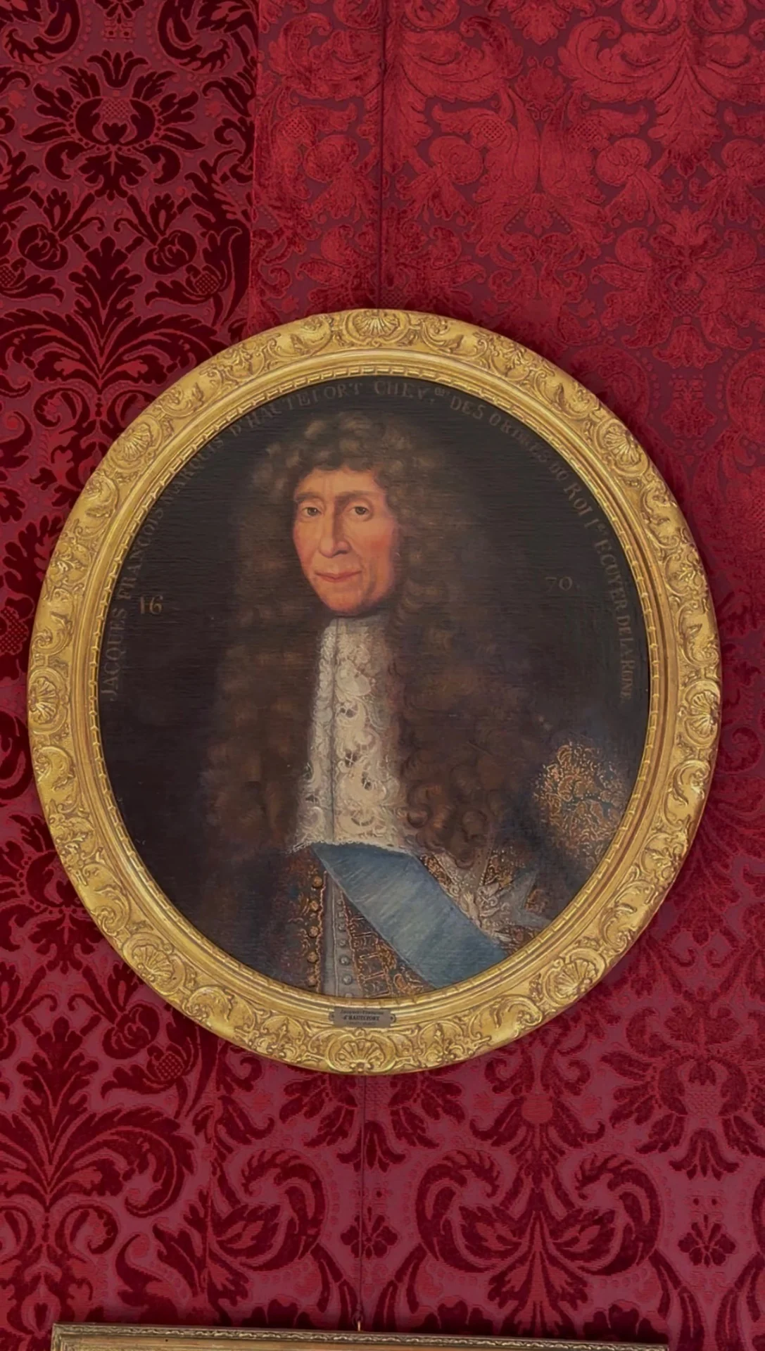 Portrait ancien dans un cadre doré sur une tenture rouge au château de Hautefort