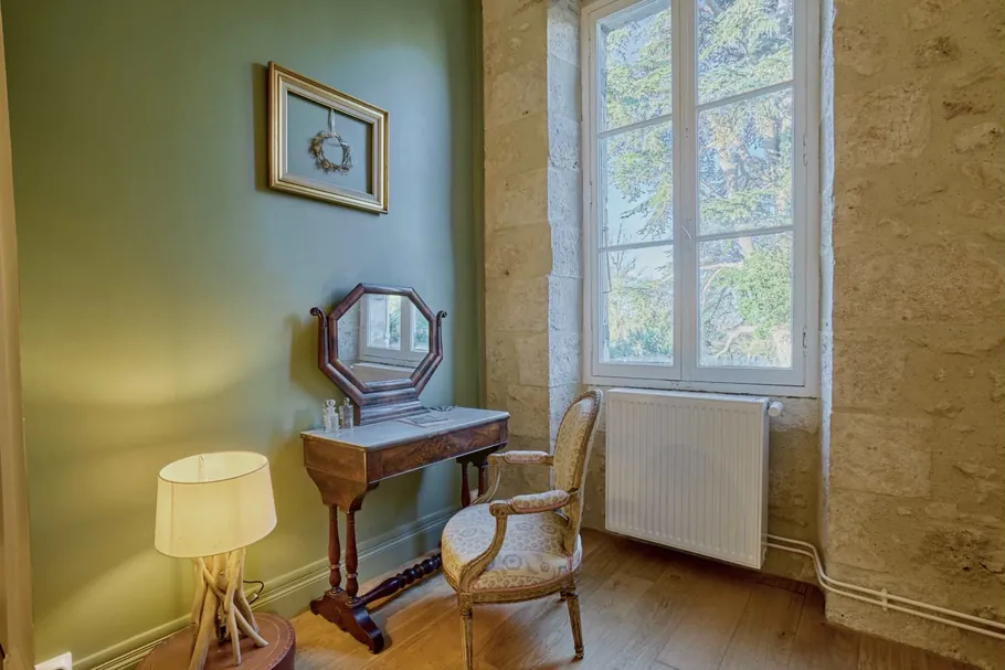 Coin coiffeuse d'époque entre mur vert sauge et pierre apparente au Clos Boissière