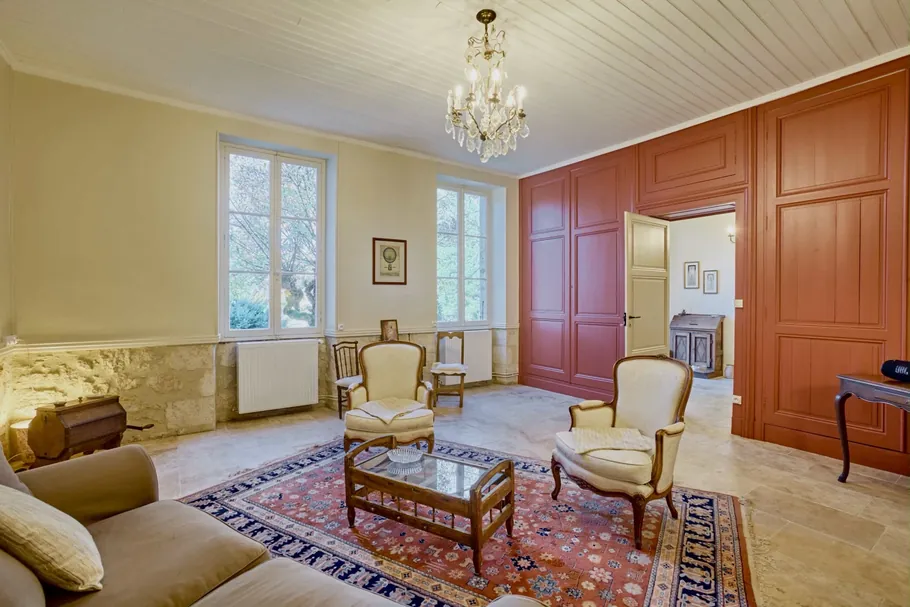 Salon aux boiseries terracotta, fauteuils d'époque et lustre en cristal au Clos Boissière