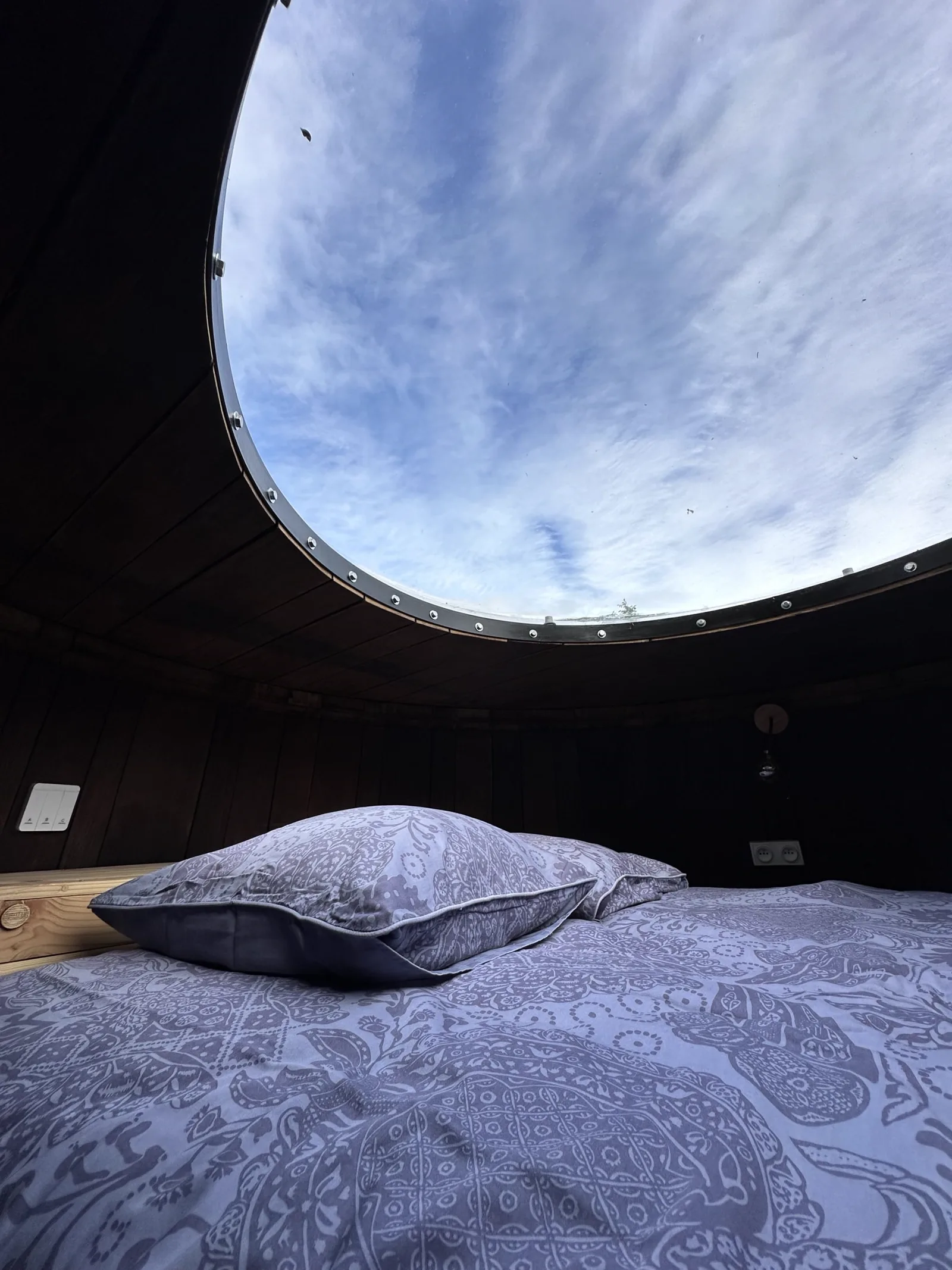 La voûte de bois et le hublot du foudre viticole aménagé en chambre